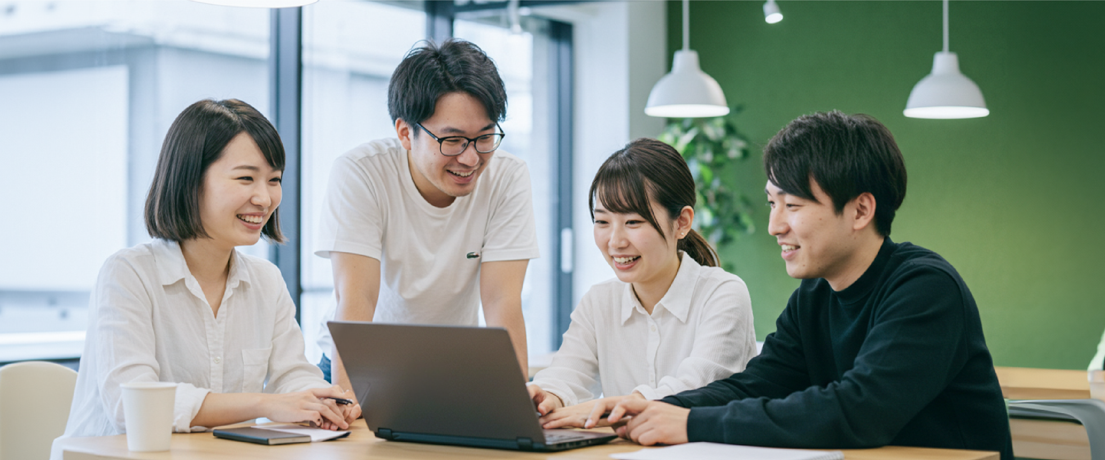 現場のメンバーと一緒にPCを見ながら業務改善を進める様子